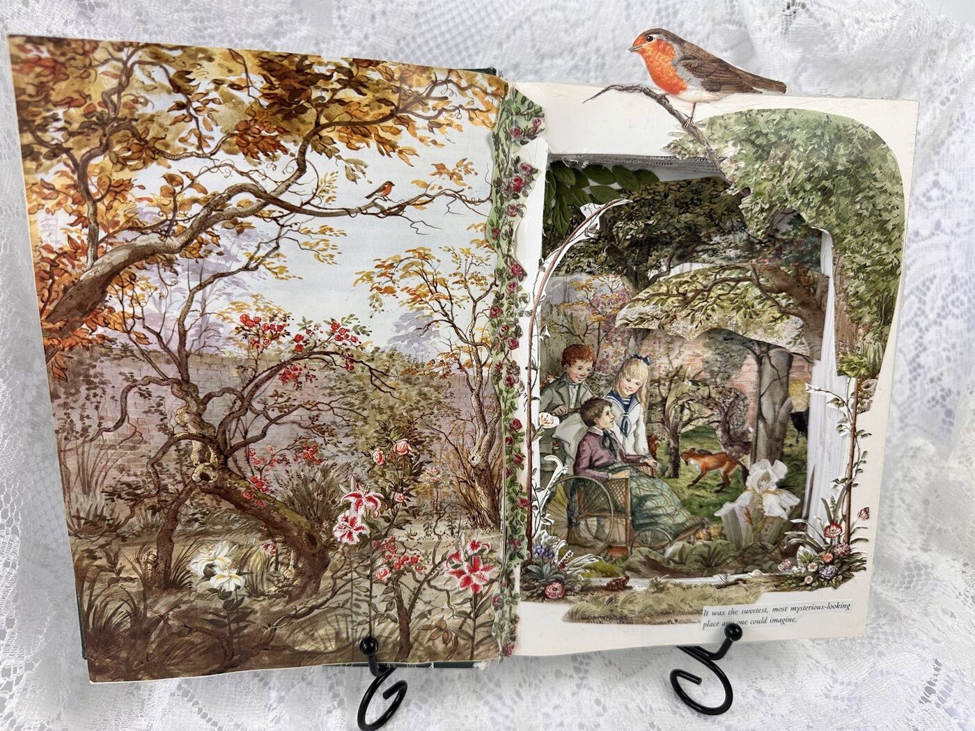 The Secret Garden book diorama, layered paper scene of children in a walled garden with a fox, framed by climbing roses and cut foliage